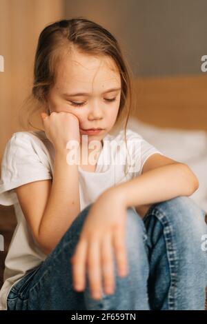 Close-up Gesicht verstört schöne kleine Mädchen mit nassen Augen von Tränen sitzt auf dem Bett im Schlafzimmer und Blick nach unten. Stockfoto