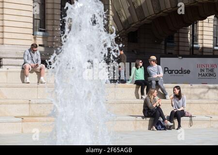 Birmingham, Großbritannien. März 2021, 30th. Büroangestellte entspannen sich am Brunnen in der Sonne auf dem neu entwickelten Chamberlain Square im Stadtzentrum von Birmingham. Kredit: Peter Lopeman/Alamy Live Nachrichten Stockfoto