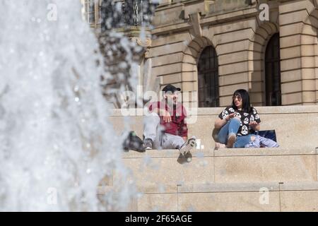 Birmingham, Großbritannien. März 2021, 30th. Büroangestellte entspannen sich am Brunnen in der Sonne auf dem neu entwickelten Chamberlain Square im Stadtzentrum von Birmingham. Kredit: Peter Lopeman/Alamy Live Nachrichten Stockfoto