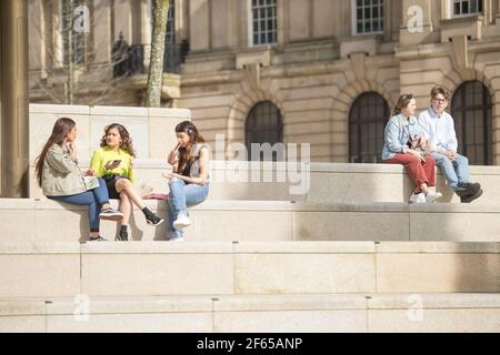 Birmingham, Großbritannien. März 2021, 30th. Büroangestellte entspannen sich in der Sonne auf dem neu entwickelten Chamberlain Square im Stadtzentrum von Birmingham. Kredit: Peter Lopeman/Alamy Live Nachrichten Stockfoto