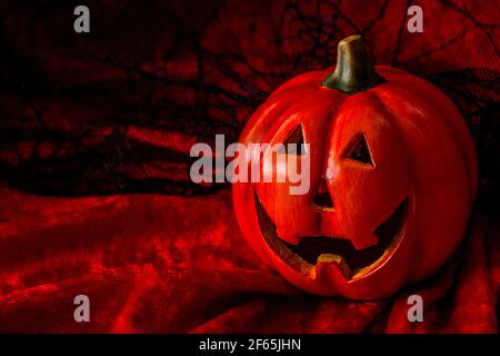 Halloween, Trick or Treat und Herbstferien Konzept mit einem Jack o'Laterne Kürbis gegen eine rote, orange und Spinnennetz schwarze Spitze Hintergrund mit Kopie Stockfoto