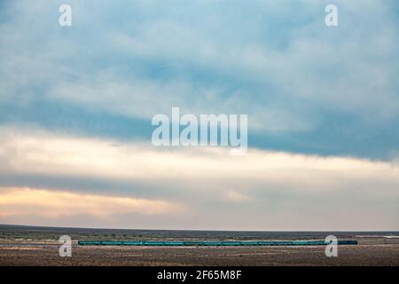 Ein grüner Zug in der Wüste mit schönem Himmel mit Wolken. Stockfoto