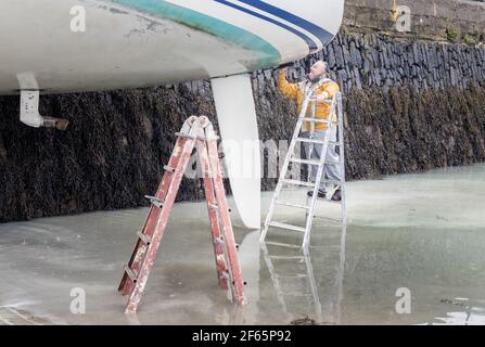 Kinsale, Cork, Irland. März 2021, 30th. Anthony McCarthy reinigt bei Ebbe den Rumpf der Familienyacht auf dem Slipway in Kinsale, Co. Cork, Irland. - Credit; David Creedon / Alamy Live News Stockfoto