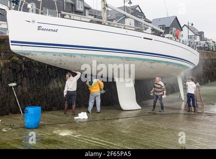 Kinsale, Cork, Irland. 30th. März 2021.LTO R; Hester, Anthony, Brian und Ross McCarthy reinigen den Rumpf der Familienyacht 'Baccarat' bei Ebbe auf dem Slipway in Kinsale, Co. Cork, Irland. - Credit; David Creedon / Alamy Live News Stockfoto