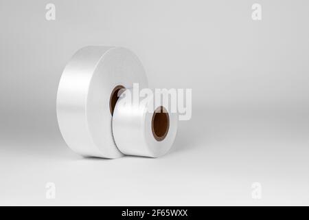 Seitenansicht Set aus zwei Spulen von breiten weißen Satinbändern für Tags oder Dekor, isoliert auf weißem, grauem Hintergrund Stockfoto
