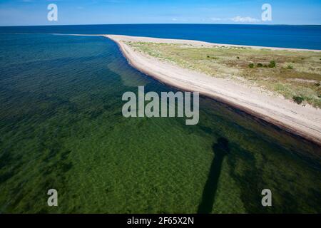 Luftaufnahme. Strand der Ostsee. 'Kiipsaare nukk' Sandspieß. Klares, transparentes Wasser und Schatten des Leuchtturms 'Kiipsaare tuletorn'. Blauer Himmel. Har Stockfoto