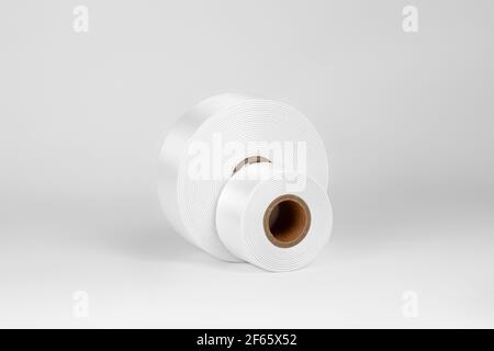 Set aus zwei Spulen von breiten weißen Satinbändern für Tags oder Dekor, isoliert auf einem weißen, grauen Hintergrund Stockfoto