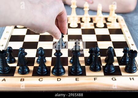 Hand einer Frau, die das Schachspiel beginnt. Konzept des Schachspiels zu Hause, Hobbys zu Hause Stockfoto