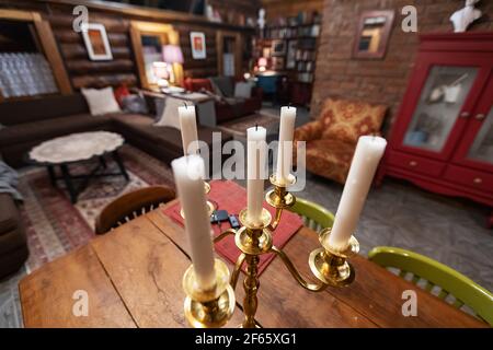 Der Kerzenhalter steht auf dem Tisch. Wachskerzen für die altmodische Raumbeleuchtung. Romantisches Abendessen bei Kerzenschein im Inneren eines Landhauses Stockfoto