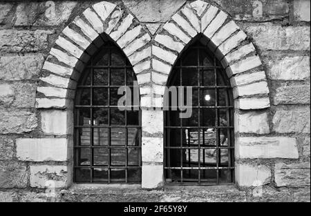 Ein Fenster mit Spitzbögen in einem mittelalterlichen Steingebäude (Marken, Italien, Europa) Stockfoto