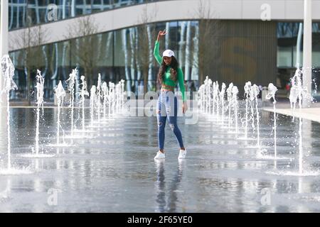 Birmingham, Großbritannien. März 2021, 30th. Eine junge Frau posiert in den Springbrunnen auf dem Centenary Square im Stadtzentrum von Birmingham. Kredit: Peter Lopeman/Alamy Live Nachrichten Stockfoto