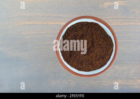 Chilipulver in einer kleinen Terrakotta-Gewürzschüssel auf einem Blau bemalter Holzhintergrund Stockfoto