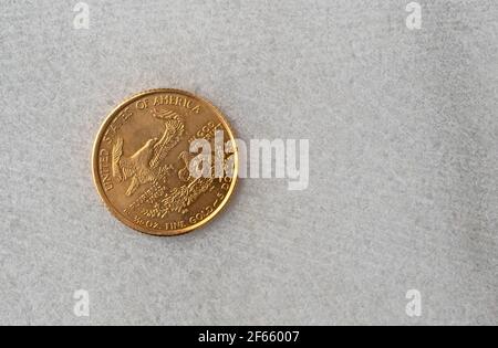 Rückseite einer Goldmünze der Vereinigten Staaten mit einem Adler, der zu einem Nest auf einer Marmoroberfläche fliegt. Stockfoto