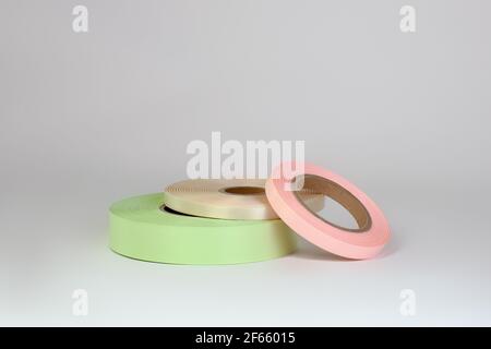 Zusammensetzung von drei Spulen von Satinbändern in rosa, grün, beige für Tags oder Branding, isoliert auf einem weißen, grauen Hintergrund Stockfoto