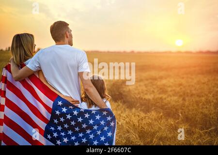 Glückliche Familie mit der Flagge von amerika USA bei Sonnenuntergang Im Freien Stockfoto
