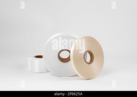 Set von drei Spulen Satinband auf der Seite für Etiketten oder DIY in weiß, beige, isoliert auf einem weißen, grauen Hintergrund Stockfoto
