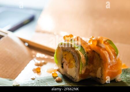 Nahaufnahme von Essstäbchen unter Teil von Sushi-Rolle auf dem Tisch Restaurant. Essen Sushi-Rolle mit Essstäbchen Stockfoto