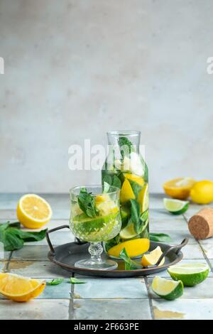 Limonade mit Zitrone und Minze in einem Glaskrug auf Fliesen Tisch, um Durst an einem heißen Sommertag zu entfernen. Stockfoto