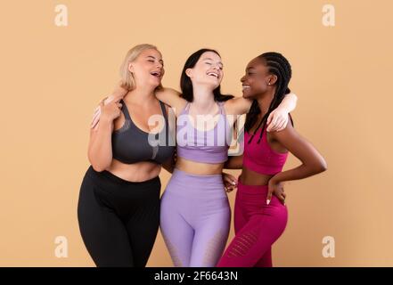 Fitness Für Alle. Glückliche Multirassische Frauen In Sportbekleidung Umarmen Und Lachen Stockfoto