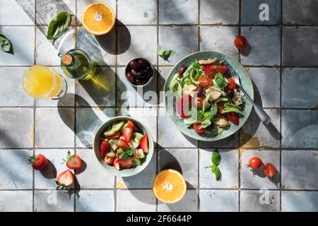 Mediterrane Gerichte am Kacheltisch: Gemüse- und Obstsalat, Zitronen- und Minzlimonade Stockfoto