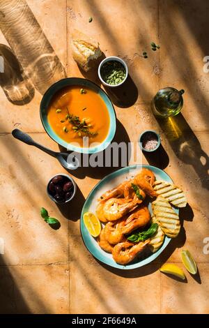 Mediterranes Mittagessen am Sandtisch: Meeresfrüchte-Garnelen, Kürbissuppe, Samen Stockfoto