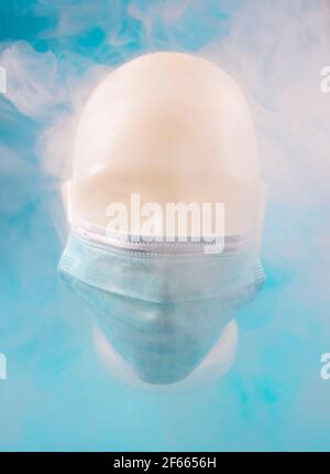Minimalistische abstrakte Komposition Hintergrund eines menschlichen Gesichts trägt eine Maske, mit Rauch bedeckt, auf einem blauen Hintergrund. Stockfoto
