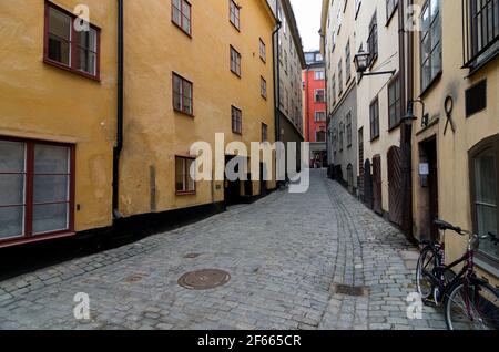 Eine schmale, gewundene, gepflasterte Seitenstraße in Gamla Stan, der Altstadt von Stockholm, Schweden. Stockfoto