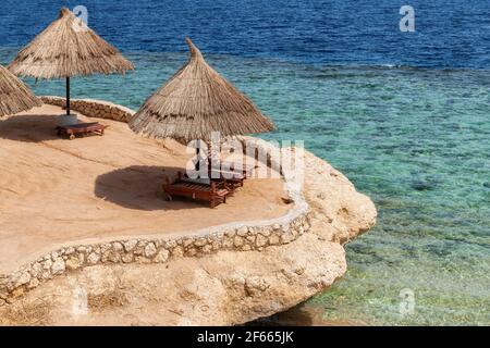 Korallenstrand mit Sonnenschirmen in Red Sea, Ägypten Stockfoto