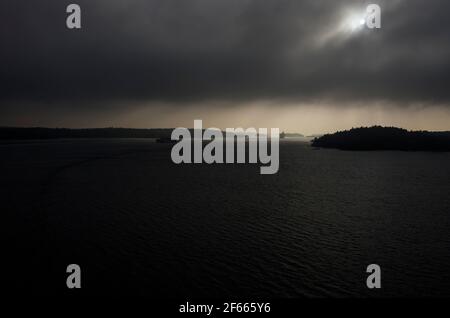 Schwerer, schwarzer Himmel und Meer mit Sonnenuntergang hinter dunklen Wolken, im Stockholmer Archipel, Ostsee, Schweden. Stockfoto