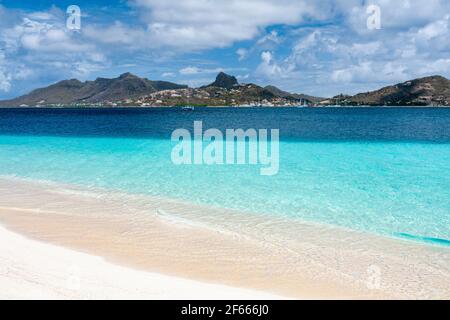 Palm Island Waters Edge-Blick auf einen ruhigen Strand mit türkisfarbenem Karibischen Meer, sanften Wellen und Blick auf Union Island mit blauem Himmel. Palm Island, Stockfoto