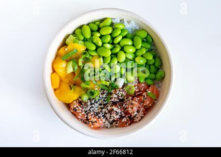 Poke eine Schüssel mit Edamame, Lachs, Mango, garniert mit Frühlingszwiebeln und Sesam auf einem Bett mit Reis Stockfoto