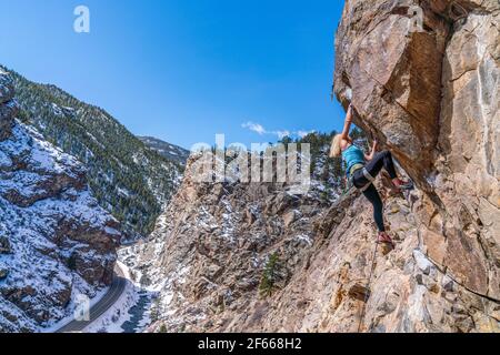 3/27/21 Golden, Colorado - Eine Frau arbeitet die Bewegungen auf einem steilen Felsklettern im Clear Creek Canyon aus. Stockfoto