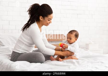 Schwarz Mutter Spielend Mit Baby Geben Spielzeug Sitzend Im Schlafzimmer Stockfoto