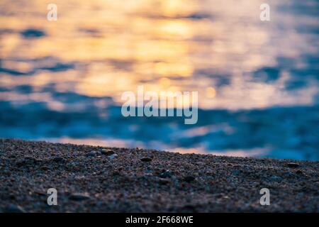 Selektive Konzentration auf den Sand am Strand bei Sonnenuntergang am Meer. Stockfoto