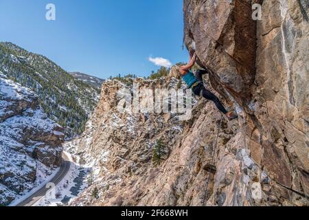 3/27/21 Golden, Colorado - Eine Frau arbeitet die Bewegungen auf einem steilen Felsklettern im Clear Creek Canyon aus. Stockfoto