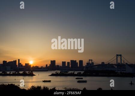 Tokio, Japan – die sonnigste und Silhouette der Skyline von Tokio und die Regenbogenbrücke, eine Hängebrücke, die die nördliche Bucht von Tokio überquert. Stockfoto