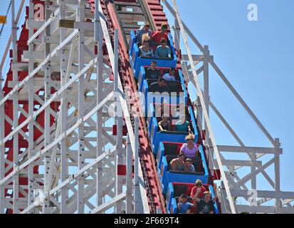 Panoramablick auf die Menschen auf dem Giant Dipper, der klassischen hölzernen Achterbahn, Wahrzeichen des Santa Cruz Vergnügungsparks in Kalifornien, USA. Stockfoto