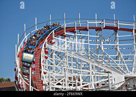 Panoramablick auf die Menschen auf dem Giant Dipper, der klassischen hölzernen Achterbahn, Wahrzeichen des Santa Cruz Vergnügungsparks in Kalifornien, USA. Stockfoto