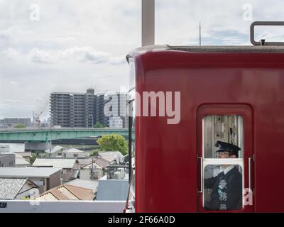 Tokio, Japan - EIN Zugfahrer, der den Bahnhof abfährt. Wohnviertel im Hintergrund. Stockfoto