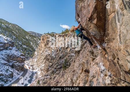 3/27/21 Golden, Colorado - Eine Frau arbeitet die Bewegungen auf einem steilen Felsklettern im Clear Creek Canyon aus. Stockfoto