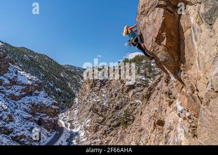 3/27/21 Golden, Colorado - Eine Frau arbeitet die Bewegungen auf einem steilen Felsklettern im Clear Creek Canyon aus. Stockfoto