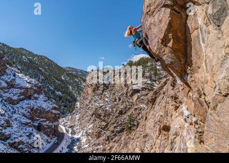 3/27/21 Golden, Colorado - Eine Frau arbeitet die Bewegungen auf einem steilen Felsklettern im Clear Creek Canyon aus. Stockfoto