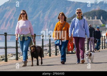 Sidmouth, Devon, Großbritannien. März 2021, 30th. Wetter in Großbritannien: Man sah die Leute an diesem Nachmittag entlang der hübschen Esplanade spazieren gehen und die heiße Sonne im hübschen Regency Resort Sidmouth genießen. Kredit: Celia McMahon/Alamy Live Nachrichten Stockfoto