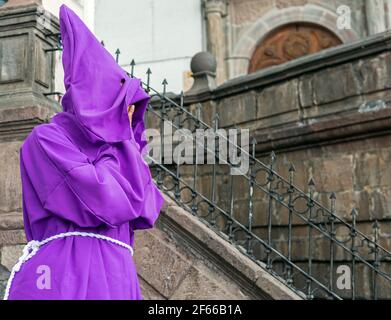 Porträt eines überdeckten Cucurucho Büßer mit violettem Umhang während der Osterprozession vor dem San Francisco Kloster in Quito, Ecuador. Stockfoto