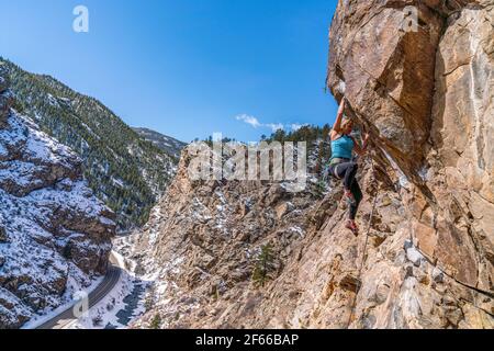 3/27/21 Golden, Colorado - Eine Frau arbeitet die Bewegungen auf einem steilen Felsklettern im Clear Creek Canyon aus. Stockfoto