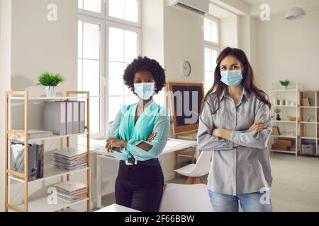 Portrait von interracial Geschäftsfrau tragen Maske im Büro Blick auf Kamera Stockfoto