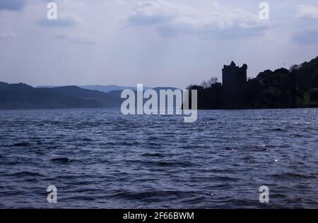 Die Silhouette von Urquhart Castle, von Loch Ness aus gesehen, an einem sonnigen Frühlingstag in Schottland, und die Berge des Great Glen im Hintergrund Stockfoto