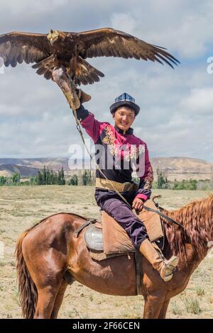 ISSYK KUL, KIRGISISTAN - 15. JULI 2018: Einheimischer mit seinem Adler beim Ethnofestival Teskey Jeek an der Küste des Issyk Kul Sees in Kirgisistan Stockfoto