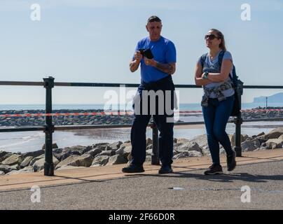Sidmouth, Devon, Großbritannien. März 2021, 30th. Wetter in Großbritannien: Die Menschen strömen in den Badeort Sidmouth, Devon, um die herrliche Sonne zu genießen, während die Südküste vor dem Osterfeiertagswochenende in einer Mini-März-Hitzewelle sonnt. Man sah die Leute an diesem Nachmittag entlang der hübschen Esplanade spazieren gehen und die heiße Sonne im hübschen Regency Resort genießen. Kredit: Celia McMahon/Alamy Live Nachrichten Stockfoto