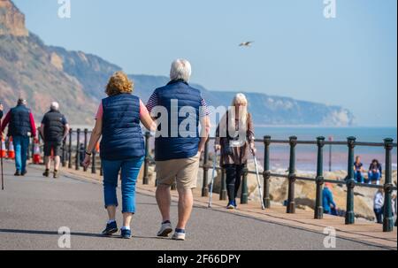 Sidmouth, Devon, Großbritannien. März 2021, 30th. Wetter in Großbritannien: Die Menschen strömen in den Badeort Sidmouth, Devon, um die herrliche Sonne zu genießen, während die Südküste vor dem Osterfeiertagswochenende in einer Mini-März-Hitzewelle sonnt. Man sah die Leute an diesem Nachmittag entlang der hübschen Esplanade spazieren gehen und die heiße Sonne im hübschen Regency Resort genießen. Kredit: Celia McMahon/Alamy Live Nachrichten Stockfoto